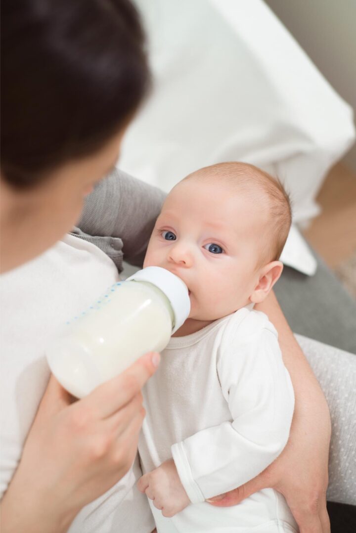Woman holding a newborn baby while feeding them with probiotics